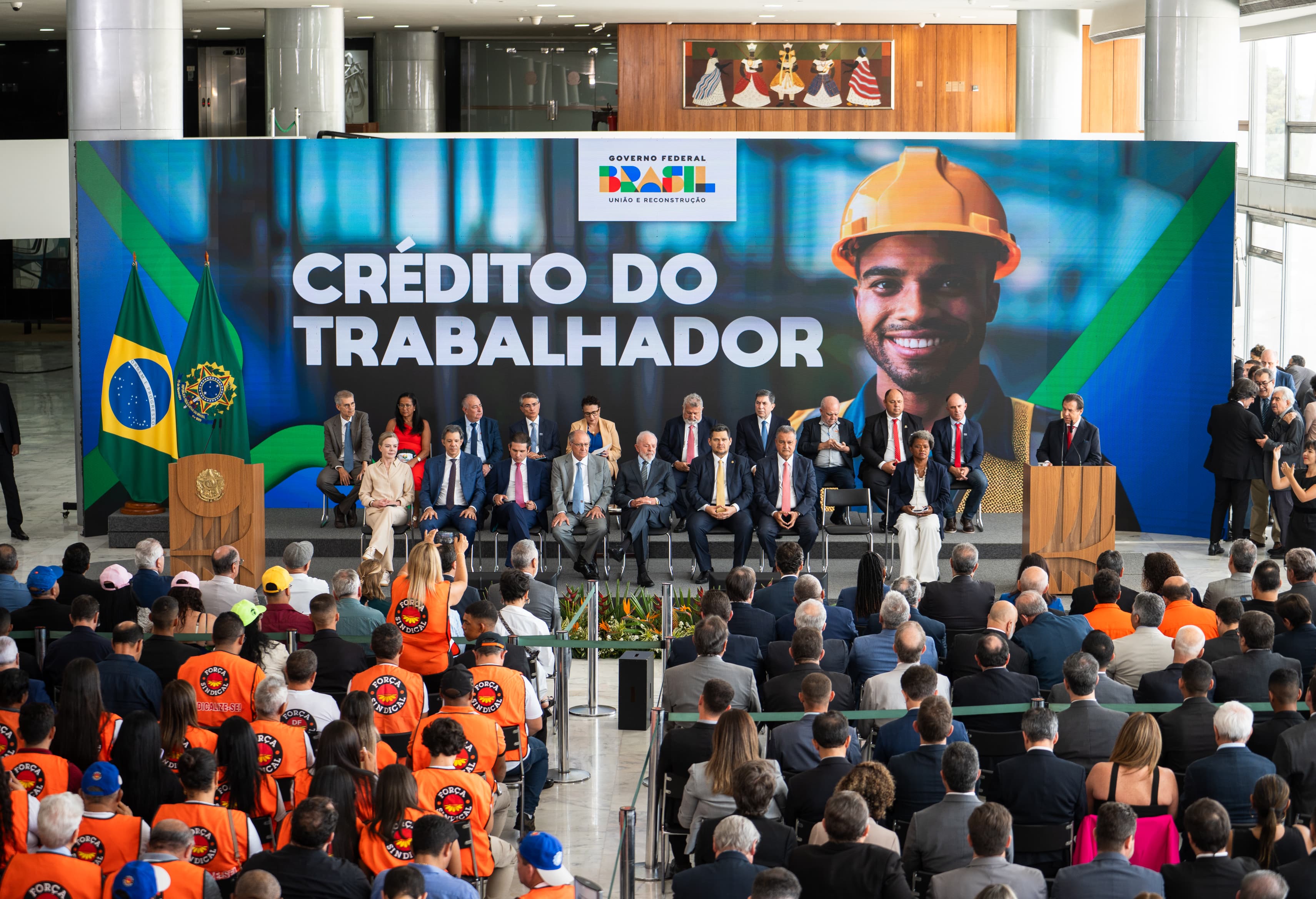 Imagem de trabalhadores em uma agência bancária, discutindo sobre o novo programa de crédito do governo